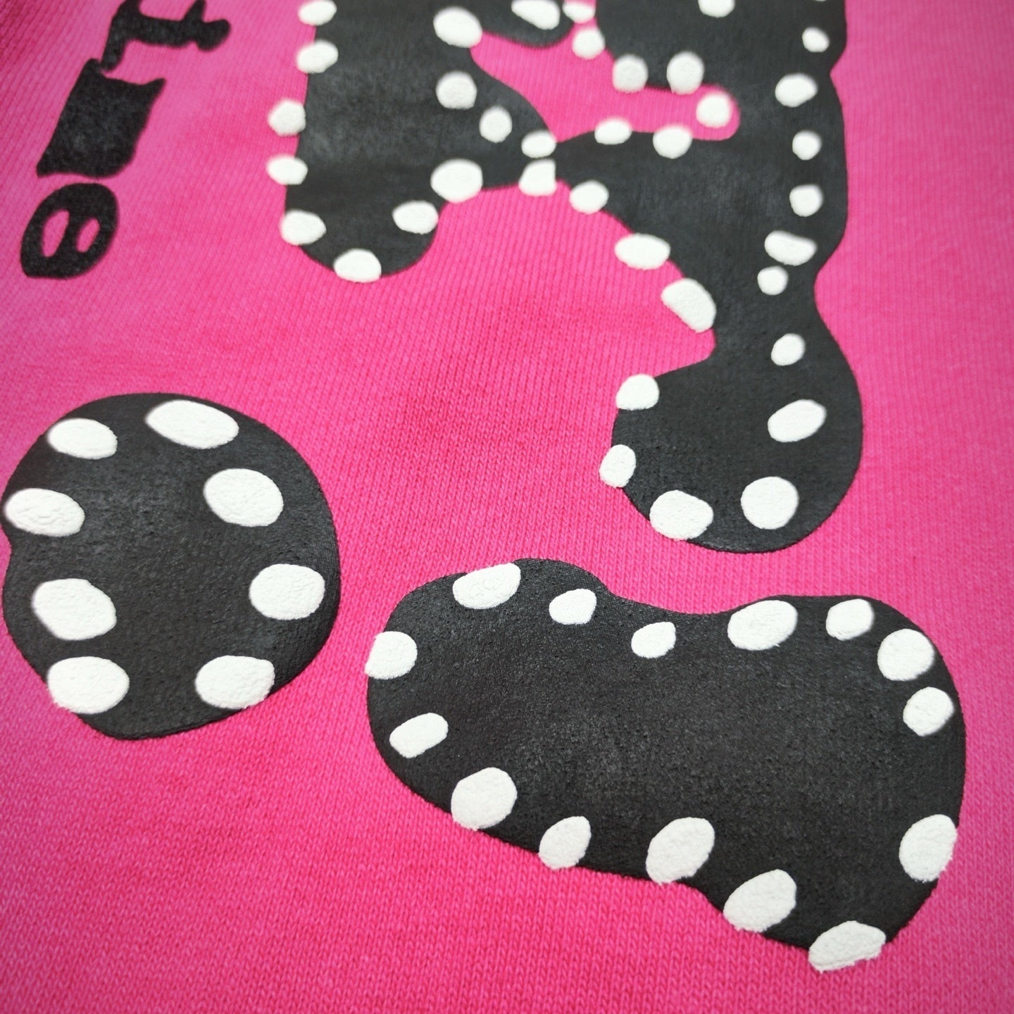 Close-up of black P*NK rhinestone leg graphic on pink Sp5der sweatpants
