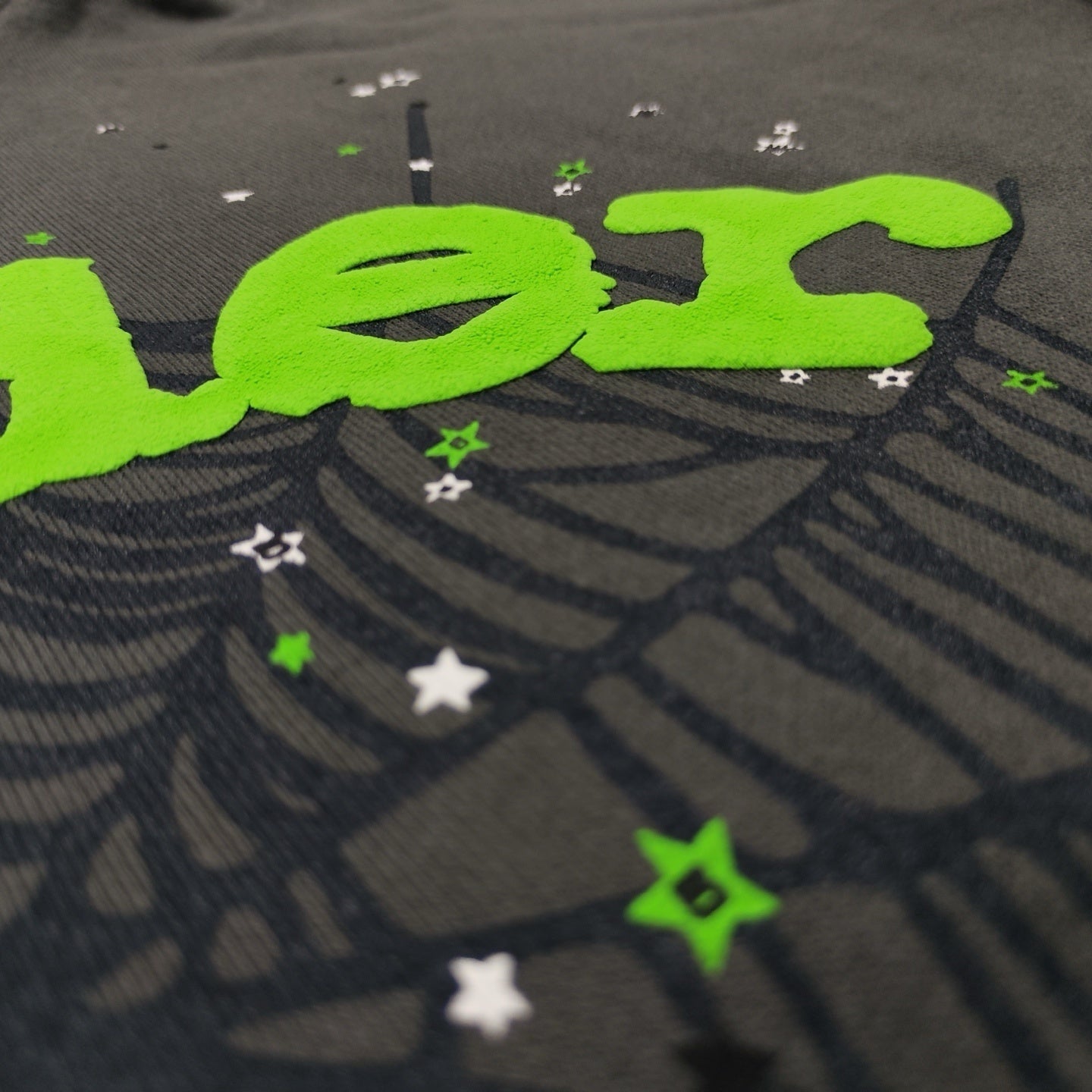 Full puff print artwork on Sp5der Wait Web Hoodie with green logo, dark web and scattered stars
Close-up of electric green puff print lettering on Sp5der Wait Web Hoodie Slate Grey
Side angle showing the raised three-dimensional puff print texture on Sp5der Slate Grey Hoodie