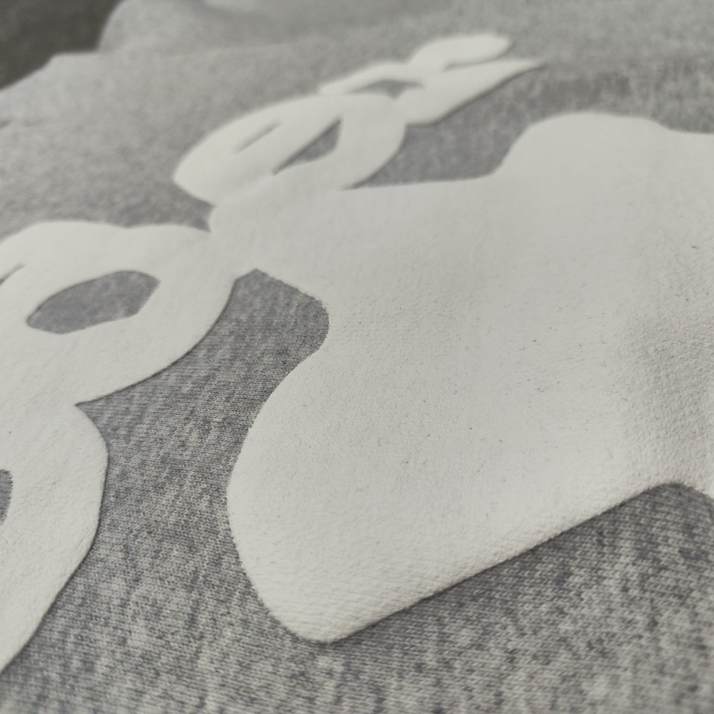 Full white puff-print artwork on Sp5der Beluga Hoodie Heather Grey with oversized logo and stars
Close-up of white puff-print lettering and star graphics on Sp5der Beluga Hoodie Heather Grey
Side angle showing the raised three-dimensional puff-print texture on Sp5der Beluga Hoodie