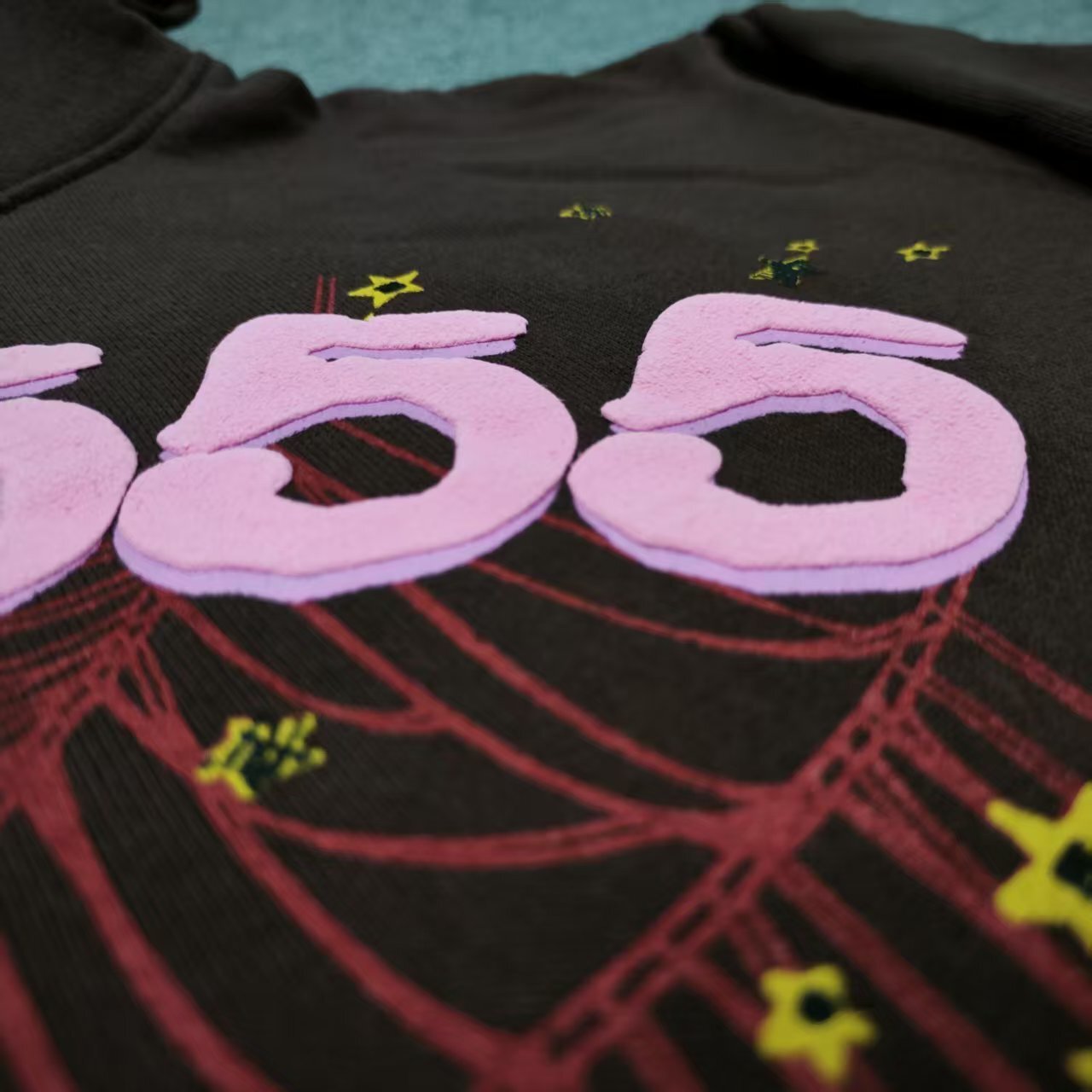 Full graphic artwork on Sp5der Angel Number Hoodie Brown with pink 555 lettering and red spider web
Close-up of raised pink 555 puff-print lettering on Sp5der Angel Number Hoodie Brown
Side angle showing the three-dimensional pink puff-print texture on Sp5der 555 Hoodie Brown