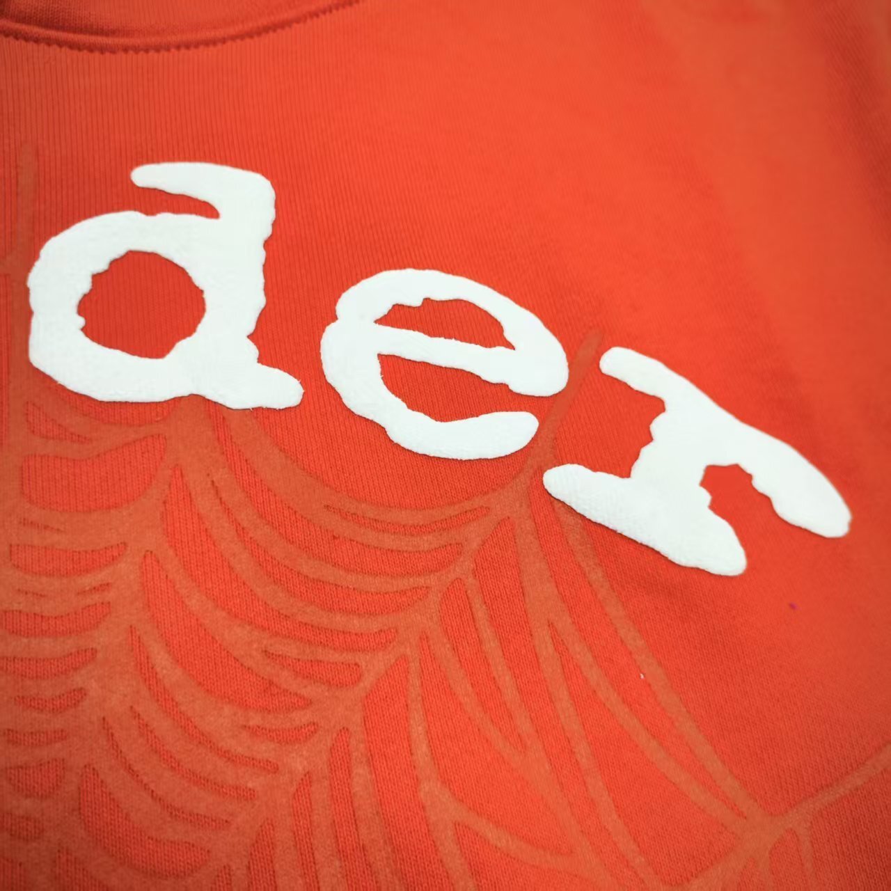 Full front artwork on Sp5der Orange Hoodie with raised white logo and tonal spider-web graphic
Close-up of raised white Sp5der lettering on the Orange Logo Hoodie Sweatshirt
Side angle showing the raised three-dimensional white logo detail on Sp5der Orange Hoodie
Close-up of tonal spider-web artwork printed across the front of Sp5der Orange Hoodie