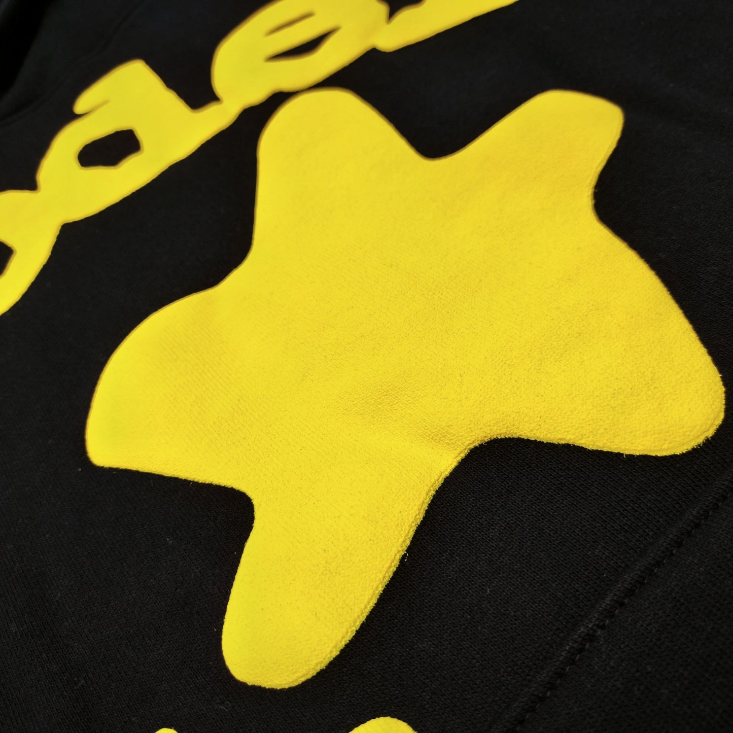 Full yellow puff-print artwork on Sp5der Beluga Hoodie Onyx Yellow with logo and star graphics
Close-up of raised yellow Sp5der lettering and smooth puff-print edges on the black Beluga Hoodie
Side angle showing the three-dimensional yellow puff-print texture on Sp5der Beluga Hoodie
Yellow star and number graphics printed across the sleeve of Sp5der Beluga Hoodie Onyx Yellow