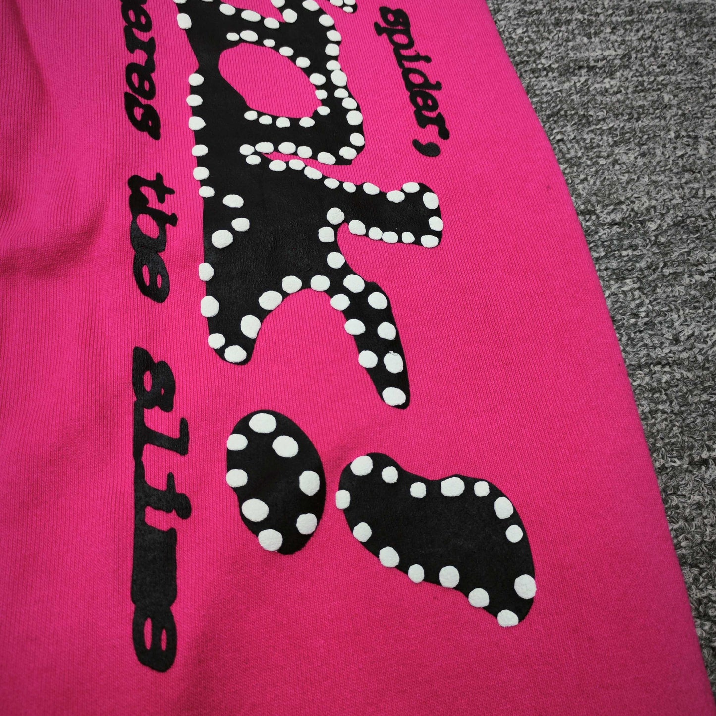 Close-up of black SP5DER puff-print graphic on pink P*NK V2 sweatpants