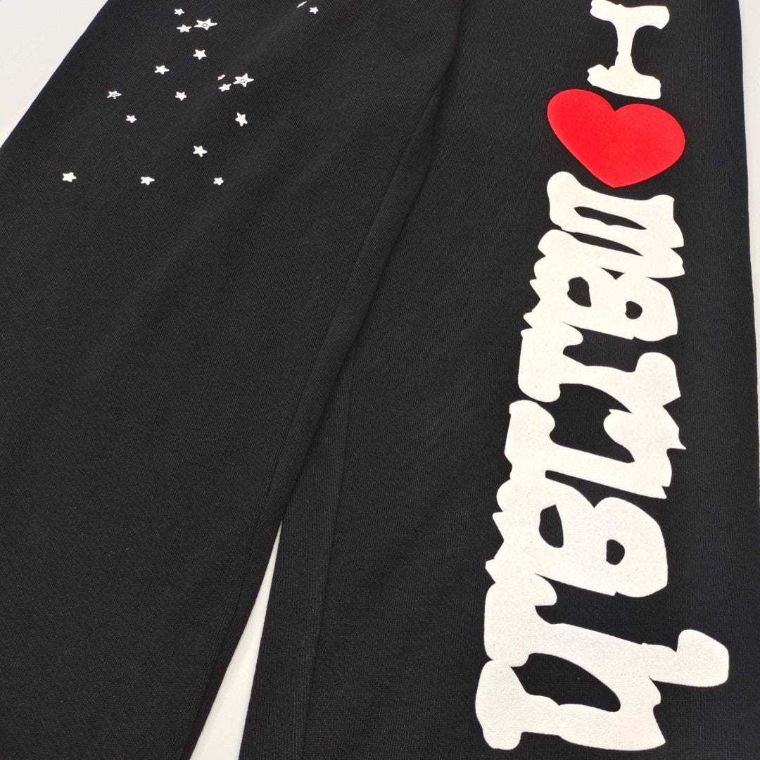 Scattered white star graphics on SP5DER Souvenir black sweatpants