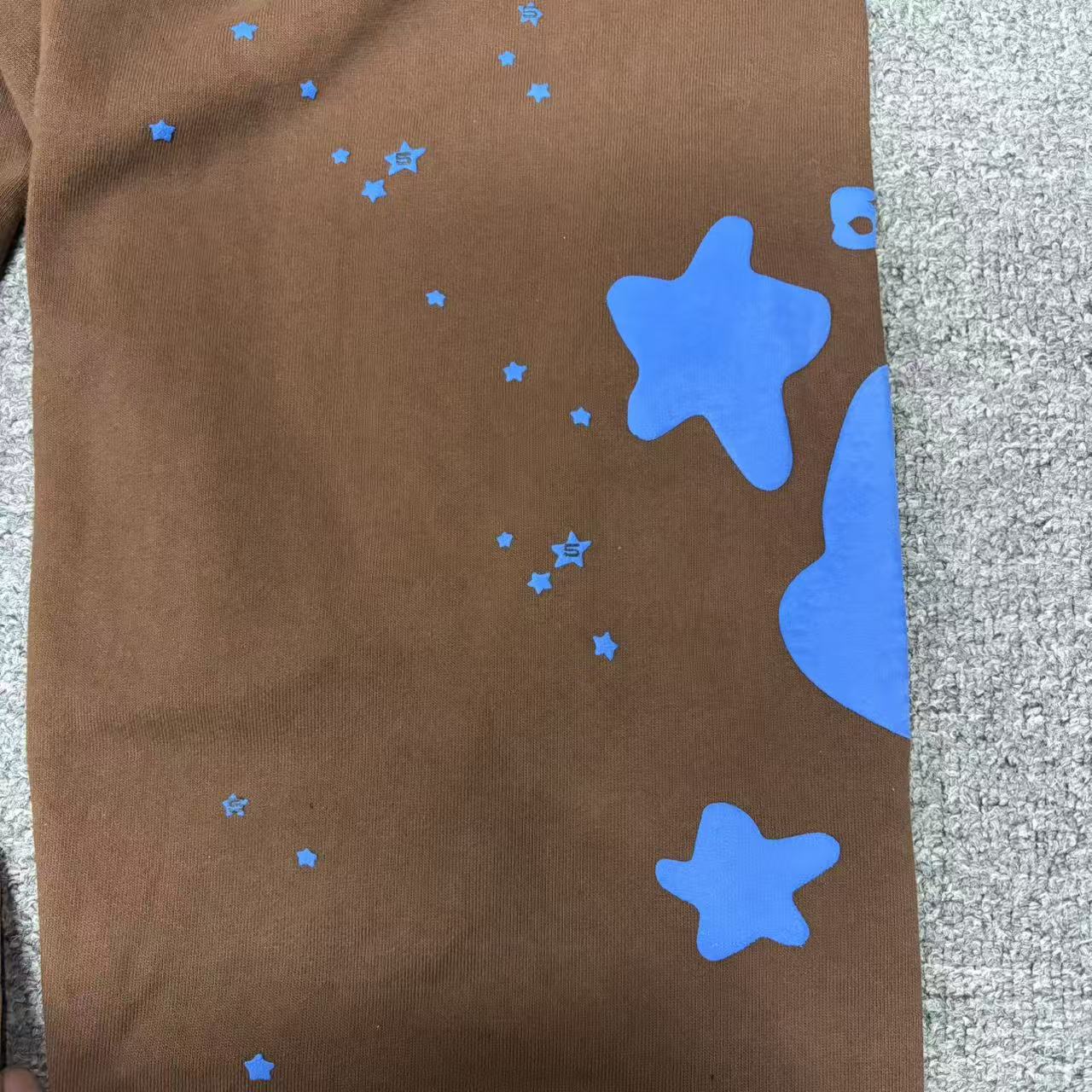 Oversized blue star graphic on SP5DER Beluga V2 brown sweatpants
Scattered blue star graphics across SP5DER Beluga V2 brown sweatpants