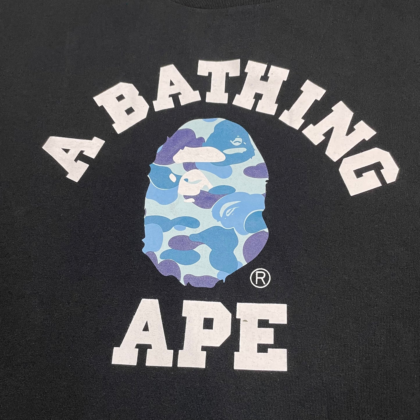 Close-up of blue ABC Camo Ape Head rubber print on black BAPE College T-shirt