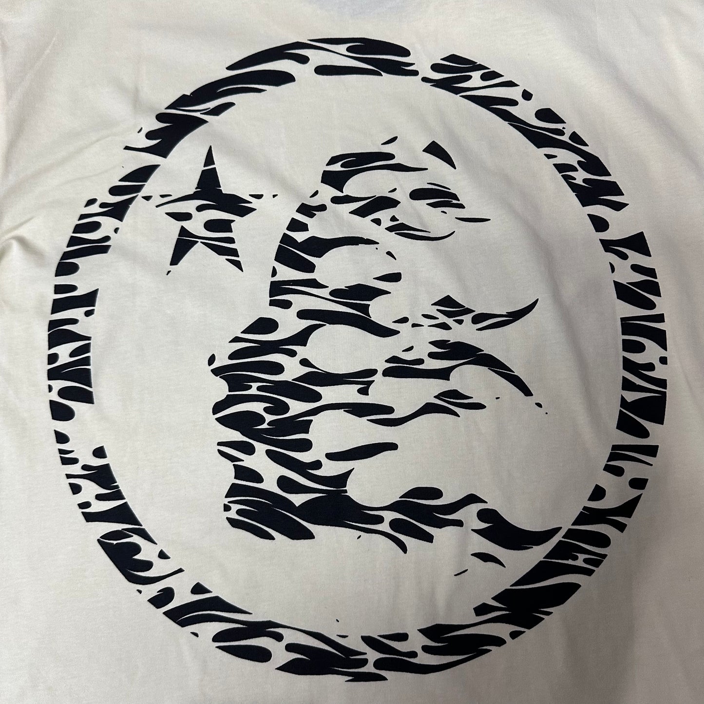 Full oversized flame-face emblem printed on the back of the Hellstar Classic Logo T-Shirt
Large circular Hellstar flame and star emblem on the back of the cream T-shirt
Black flame-profile character graphic on the back of the Hellstar Classic T-Shirt
Close-up of the flame-profile face inside the circular Hellstar back emblem