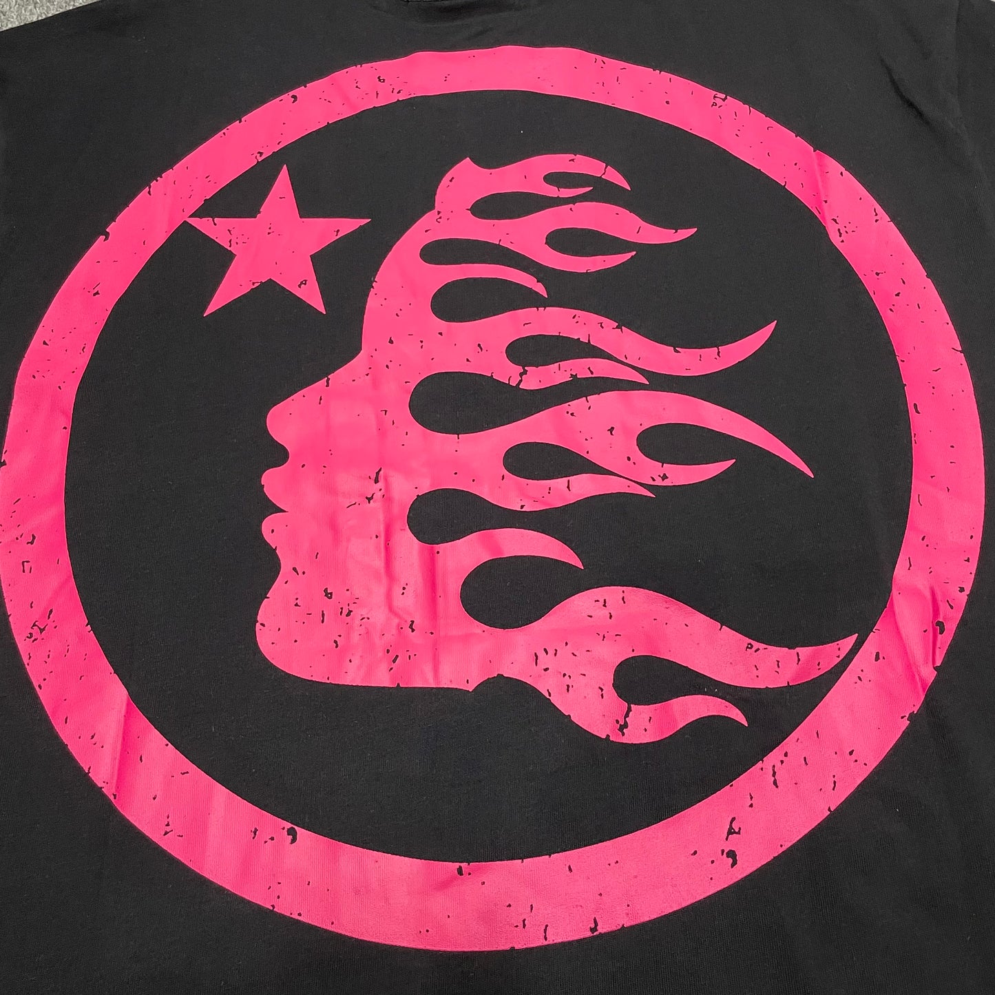 Full oversized pink circular graphic printed on the back of the Hellstar Adventure T-Shirt
Pink flame-profile character inside the circular back graphic on the Hellstar T-Shirt
White star detail inside the oversized pink Hellstar back graphic