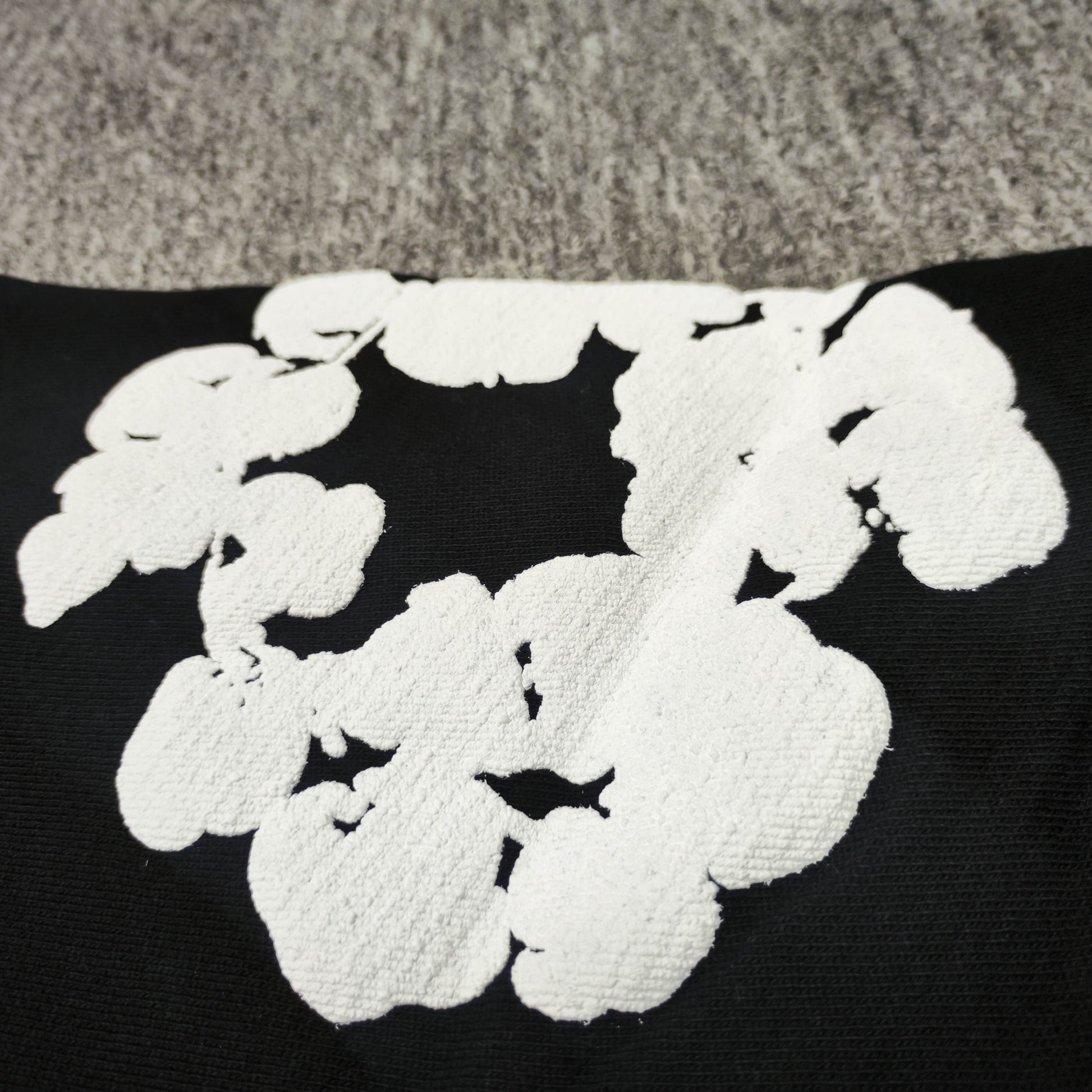 Black Cotton Wreath Hoodie with all-over white puff print
Close-up of white Cotton Wreath puff print on Black hoodie
Raised 3D Cotton Wreath puff print texture on Black hoodie