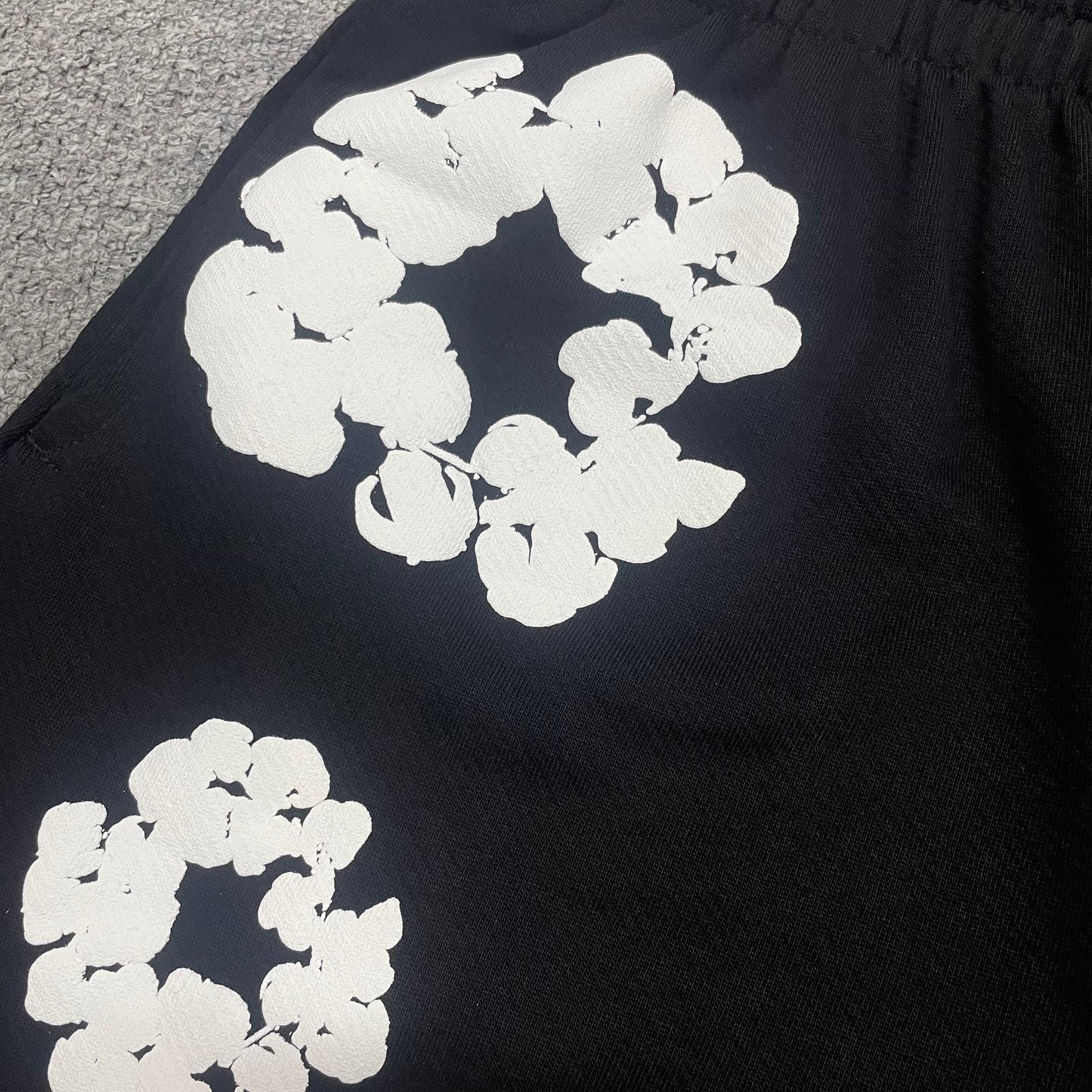 Black Cotton Wreath Sweatshorts with all-over white puff print
Close-up of white Cotton Wreath puff print on Black sweatshorts
Raised 3D Cotton Wreath puff print texture on Black sweatshorts