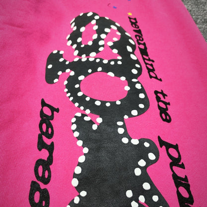 Close-up of black P*NK rhinestone leg graphic on pink Sp5der sweatpants