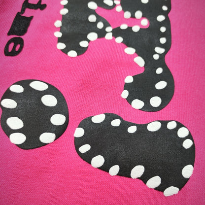 Close-up of black P*NK rhinestone leg graphic on pink Sp5der sweatpants