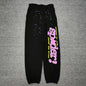 Sp5der P*NK sweatpants black front view with pink rhinestone logo and multicolor star graphics
