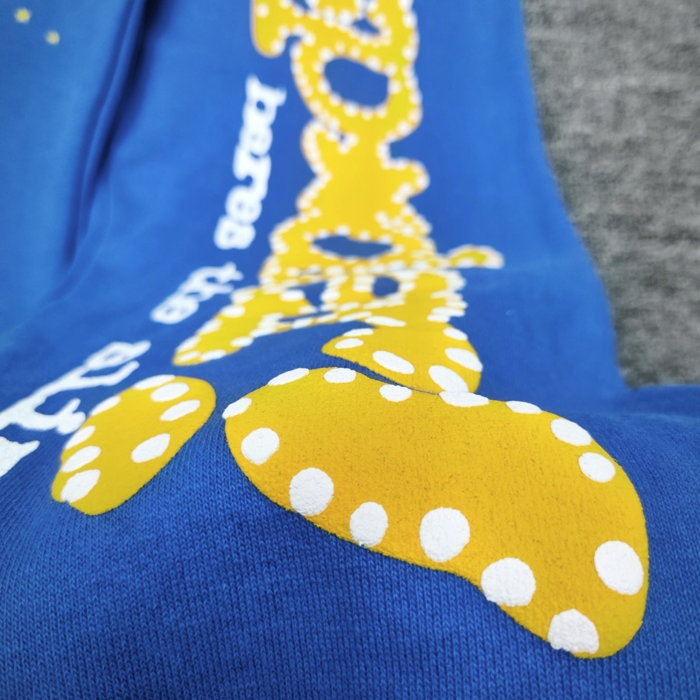 Close-up of yellow SP5DER puff-print graphic on blue sweatpants
Close-up of white Beyond the Slime text print on SP5DER TC Blue sweatpants
Raised puff-print texture detail on SP5DER TC Blue graphic sweatpants