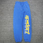 SP5DER TC Blue sweatpants front view with yellow leg graphic and multicolor star details