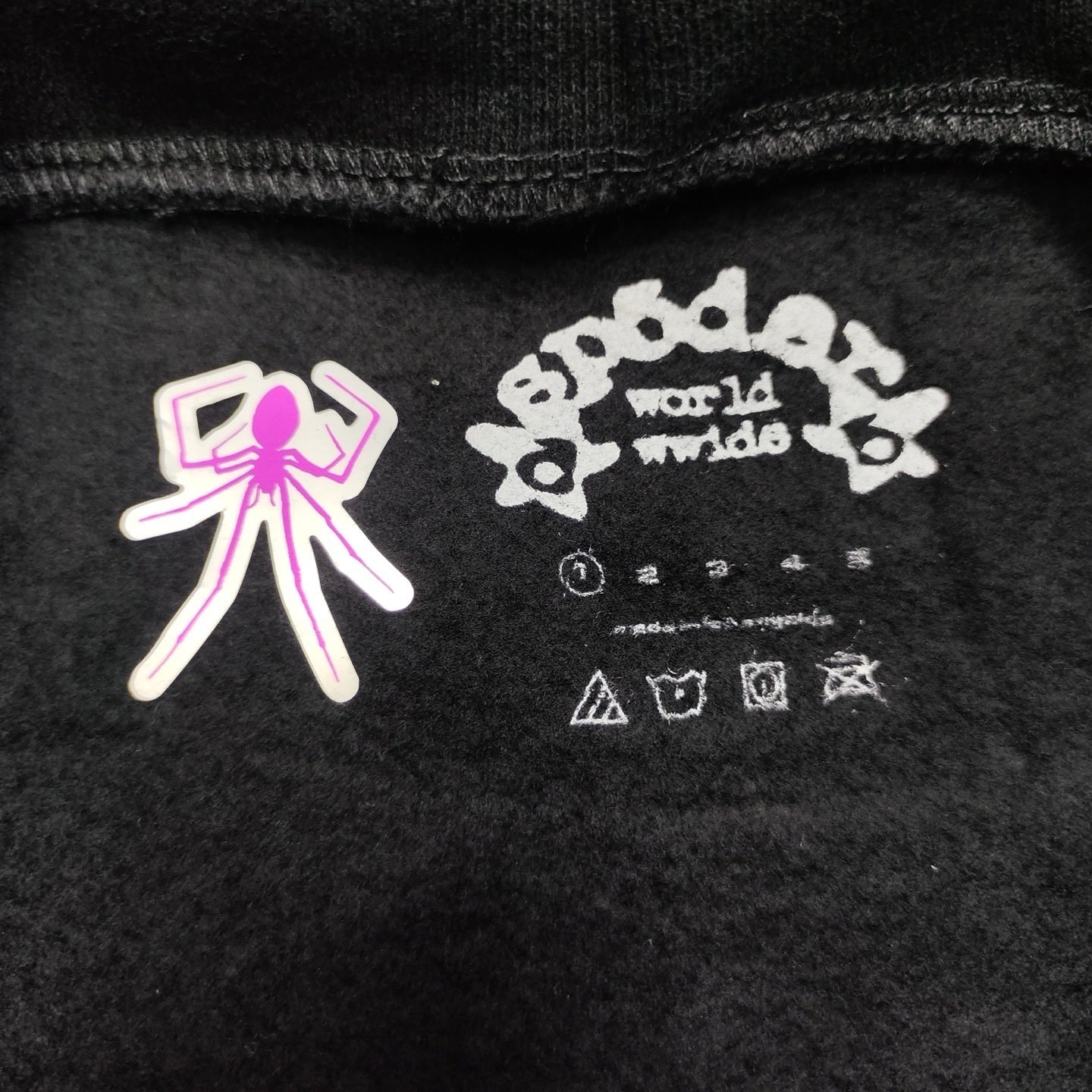 Sp5der P*nk Hoodie Black neck label and size tag detail
Sp5der P*nk Hoodie Black care label and washing instruction detail