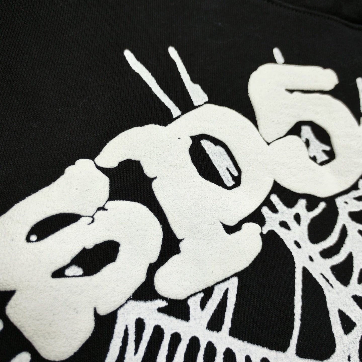 Full white puff-print artwork on Sp5der OG Web Hoodie Black with oversized logo and spider web
Close-up of raised white Sp5der lettering and web print details on the black OG Web Hoodie
Side angle showing the three-dimensional white puff-print texture on Sp5der OG Web Hoodie Black