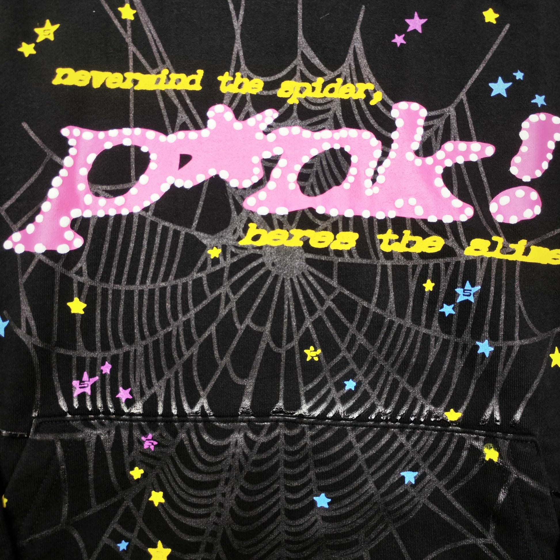 Full graphic artwork on Sp5der P*NK Hoodie Black with pink puff lettering, web print and colorful stars
Close-up of raised pink P*NK lettering and white dot details on Sp5der Black Hoodie
Side angle showing the three-dimensional pink puff-print texture on Sp5der P*NK Hoodie Black