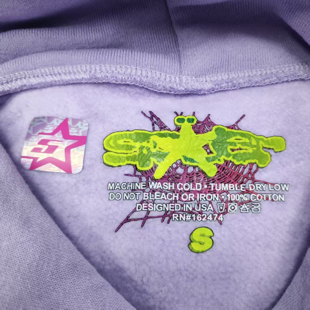 Sp5der Acai Hoodie Purple neck label and size tag detail
Sp5der Acai Hoodie Purple care label and washing instruction detail
