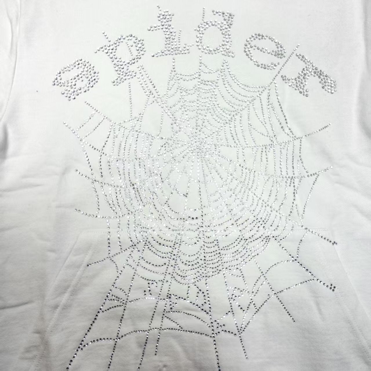 Full rhinestone artwork on Sp5der OG Logo Hoodie White with crystal lettering and spider web
Close-up of silver rhinestone Sp5der lettering and crystal web details on the white hoodie
Side angle showing the raised three-dimensional rhinestone texture on Sp5der White Hoodie