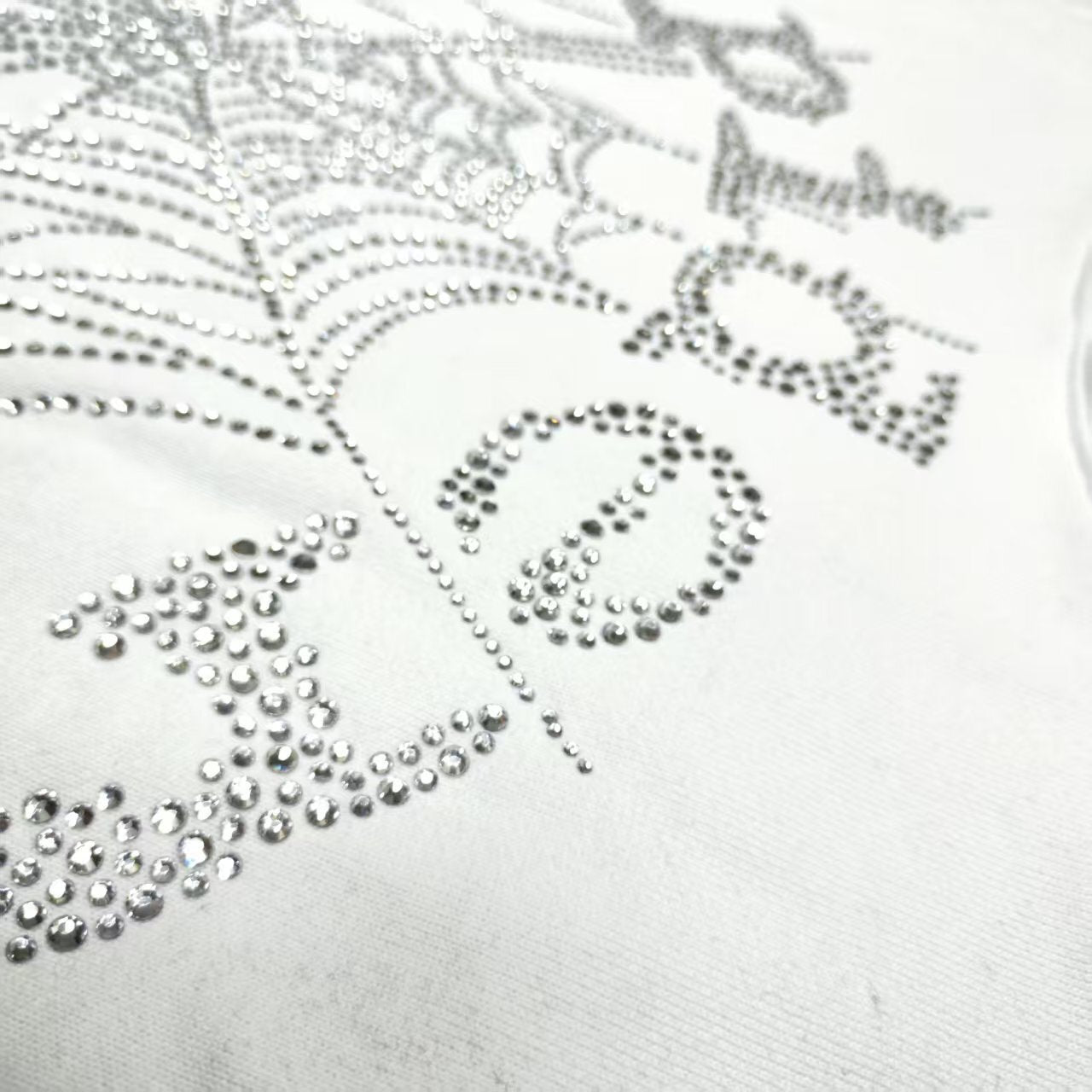 Full rhinestone artwork on Sp5der OG Logo Hoodie White with crystal lettering and spider web
Close-up of silver rhinestone Sp5der lettering and crystal web details on the white hoodie
Side angle showing the raised three-dimensional rhinestone texture on Sp5der White Hoodie