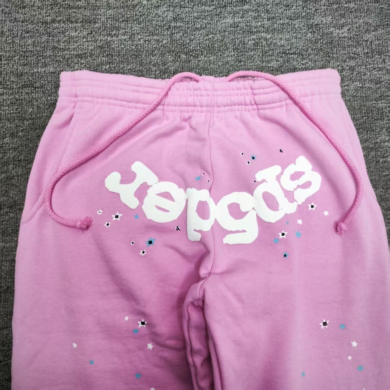 Close-up of raised white SP5DER puff-print logo on pink Atlanta sweatpants
Drawstring end and finishing detail on SP5DER Atlanta pink sweatpants