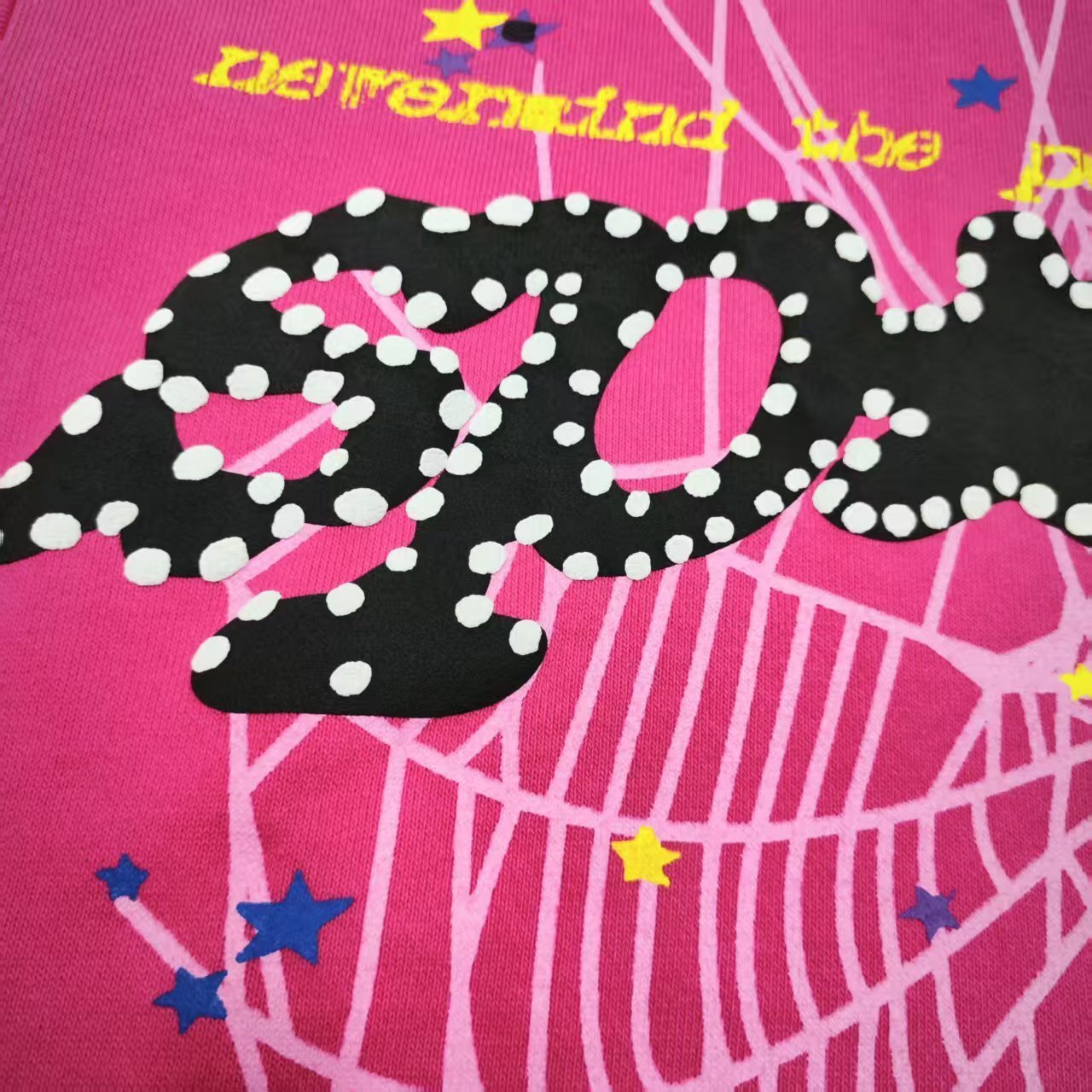Full puff-print artwork on Sp5der P*NK V2 Hoodie Pink with black logo, white web and stars
Close-up of raised black SP5DER lettering with white dot details on the pink V2 hoodie
Side angle showing the three-dimensional puff-print texture on Sp5der P*NK V2 Hoodie Pink