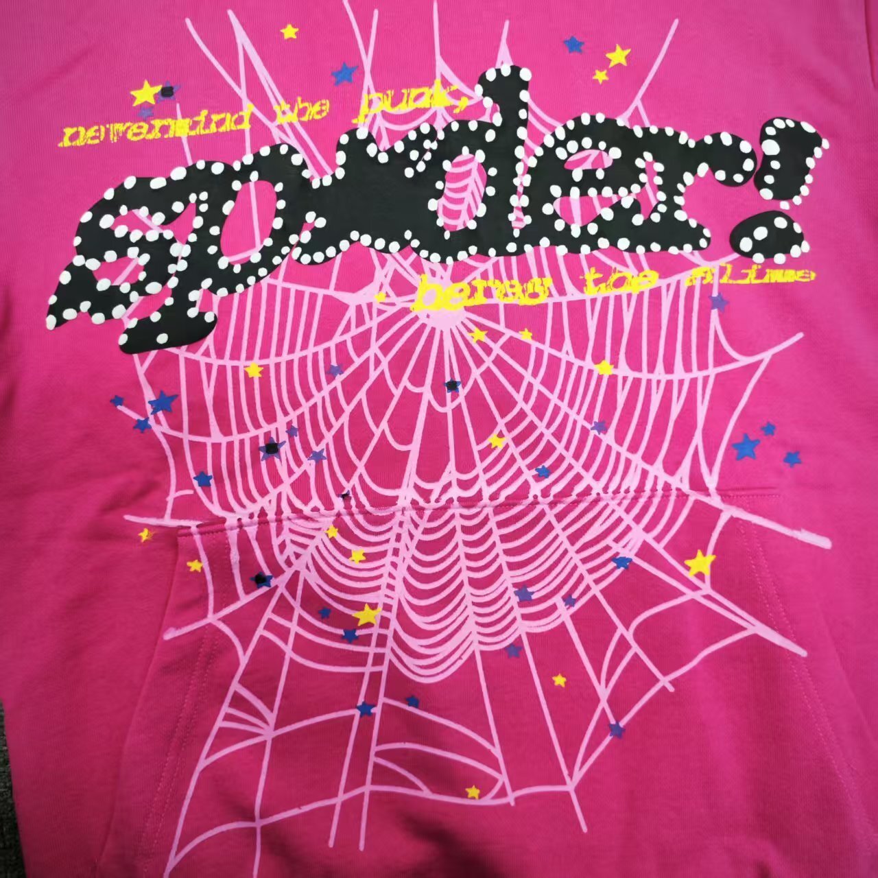 Full puff-print artwork on Sp5der P*NK V2 Hoodie Pink with black logo, white web and stars
Close-up of raised black SP5DER lettering with white dot details on the pink V2 hoodie
Side angle showing the three-dimensional puff-print texture on Sp5der P*NK V2 Hoodie Pink