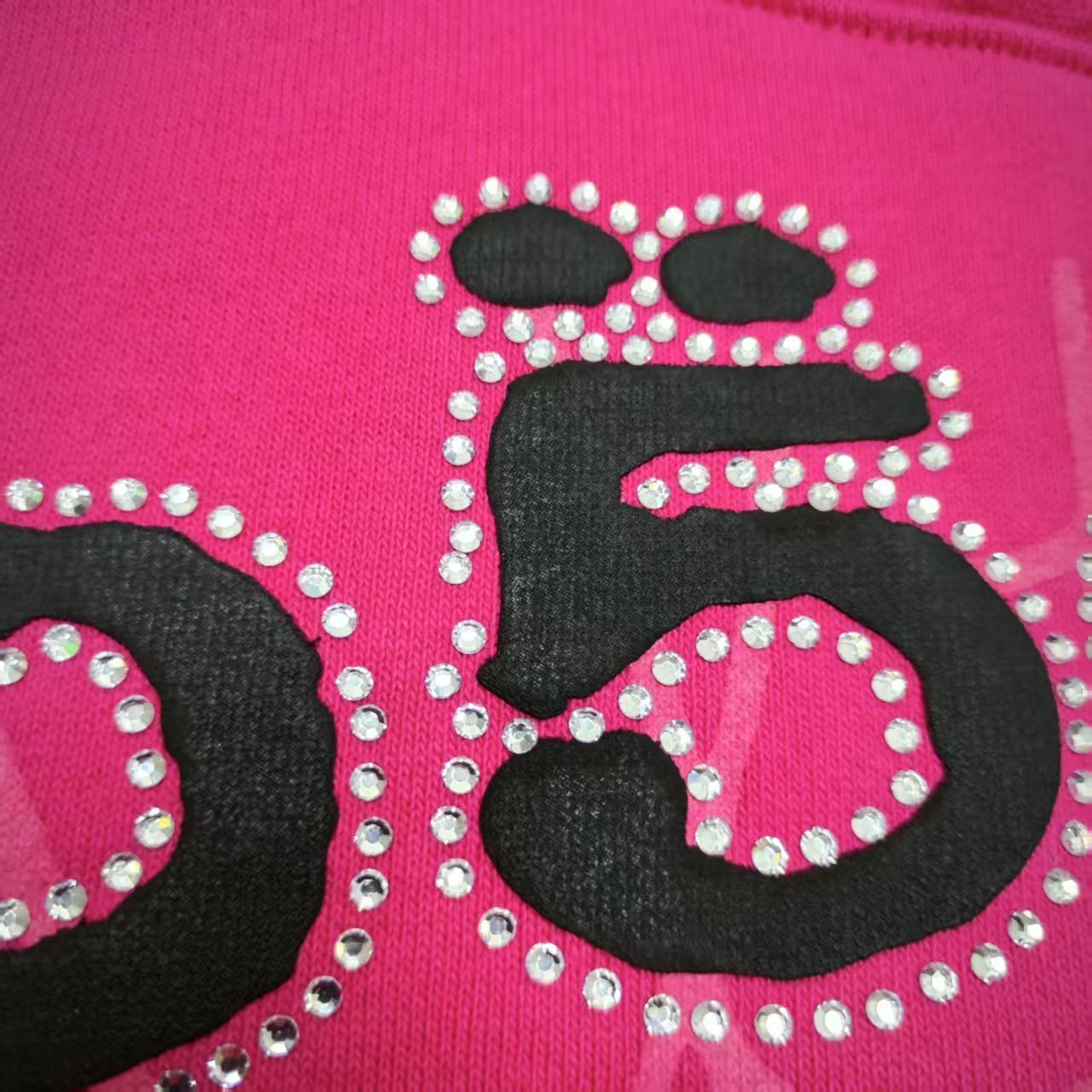 Full front artwork on Sp5der Legacy Hoodie Pink White with puff lettering, rhinestones and spider web
Close-up of raised black SP5DER puff-print lettering on the pink Legacy Hoodie
Close-up of rhinestone trim surrounding the black SP5DER lettering on the pink Legacy Hoodie
Side angle showing raised puff lettering and three-dimensional rhinestone details on Sp5der Legacy Hoodie