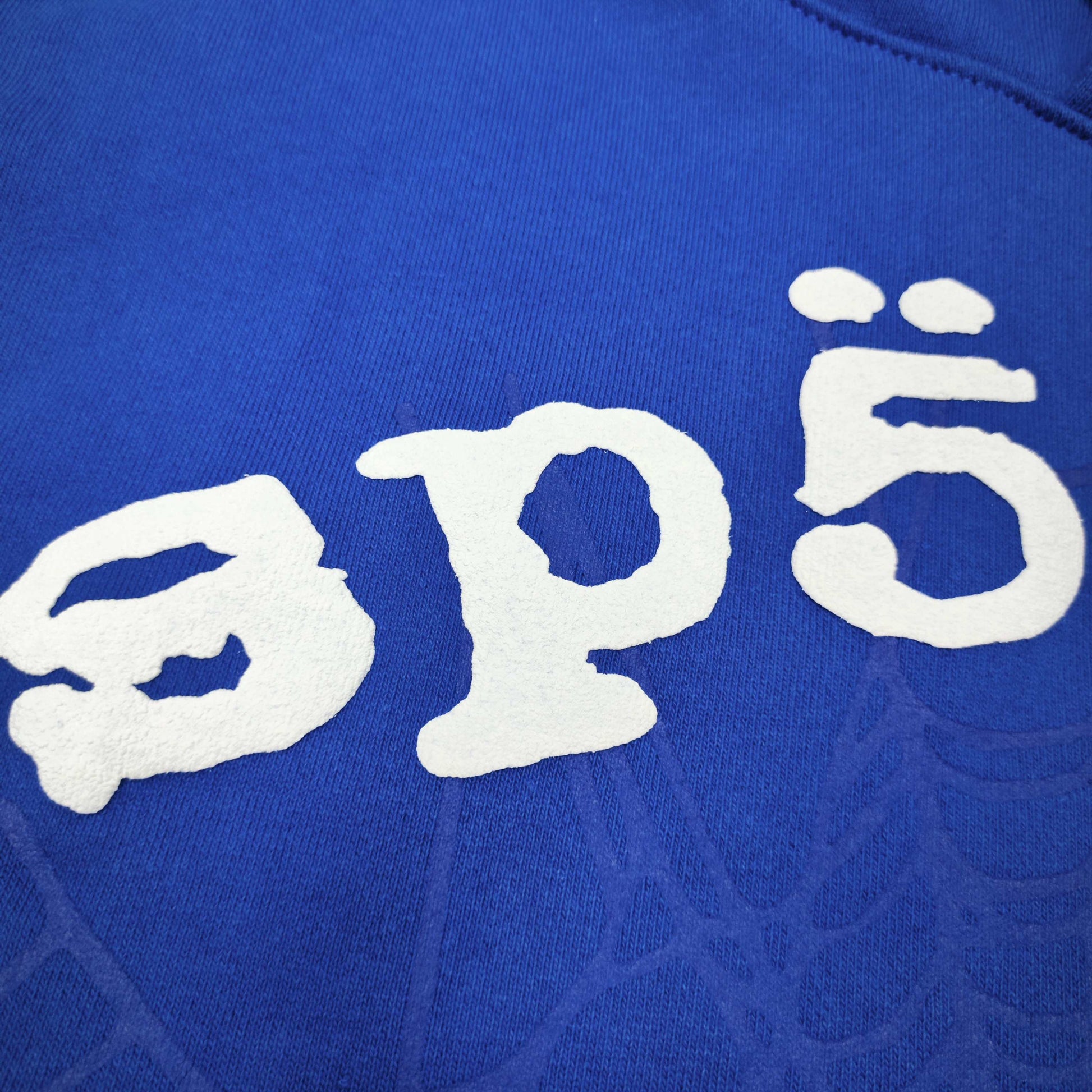 Full front artwork on Sp5der Logo Hoodie Blue with raised white logo and tonal web graphic
Close-up of raised white Sp5der lettering on the Blue Logo Hoodie
Side angle showing the three-dimensional raised white logo detail on Sp5der Blue Hoodie
Close-up of tonal spider-web artwork across the front of Sp5der Logo Hoodie Blue