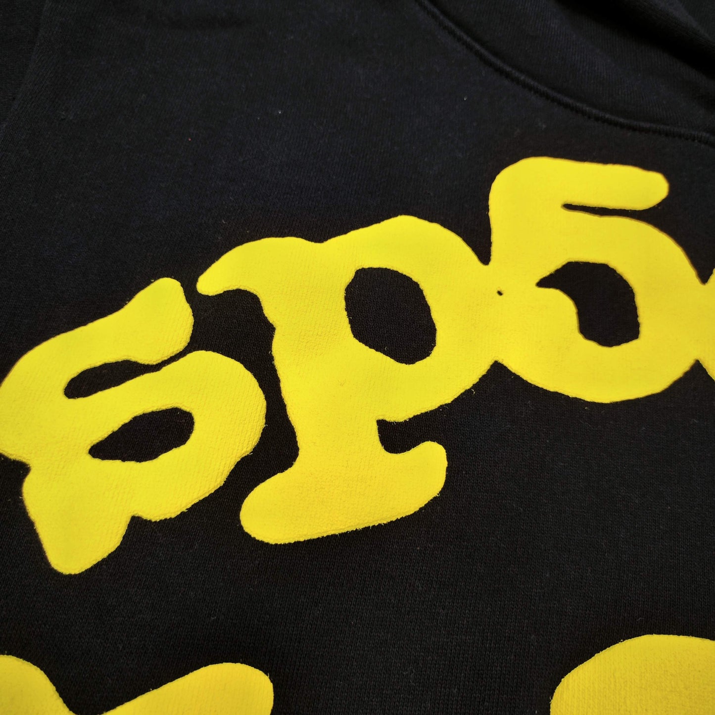 Full yellow puff-print artwork on Sp5der Beluga Hoodie Onyx Yellow with logo and star graphics
Close-up of raised yellow Sp5der lettering and smooth puff-print edges on the black Beluga Hoodie
Side angle showing the three-dimensional yellow puff-print texture on Sp5der Beluga Hoodie
Yellow star and number graphics printed across the sleeve of Sp5der Beluga Hoodie Onyx Yellow