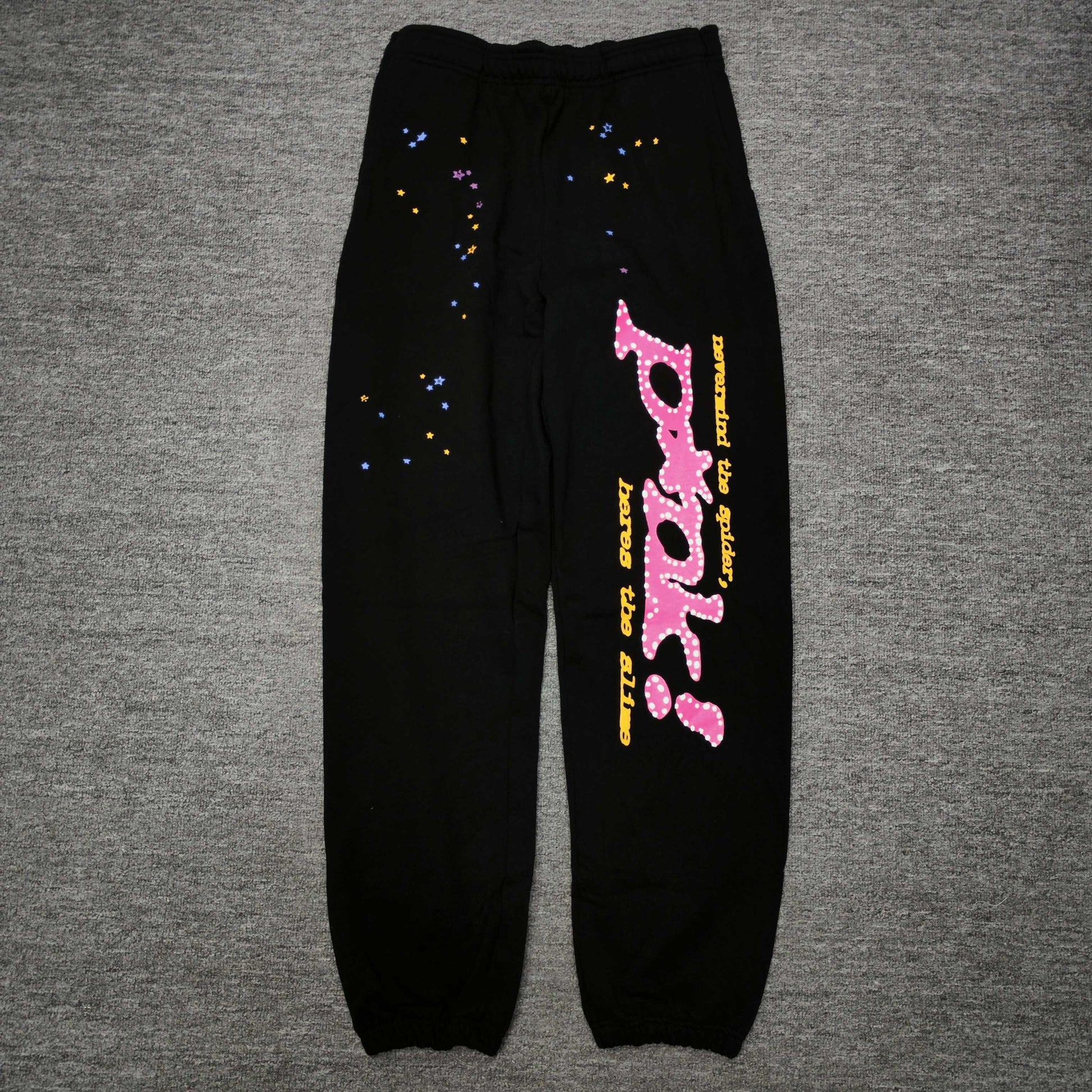 SP5DER P*NK V2 black sweatpants front view with pink leg graphic and multicolor stars