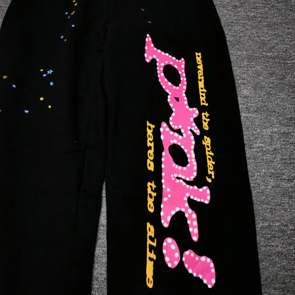 Close-up of pink SP5DER puff-print graphic on black P*NK V2 sweatpants
Raised pink puff-print texture on SP5DER P*NK V2 black sweatpants
Close-up of defined puff-print edges on SP5DER P*NK V2 sweatpants
Yellow slogan print detail on SP5DER P*NK V2 black sweatpants