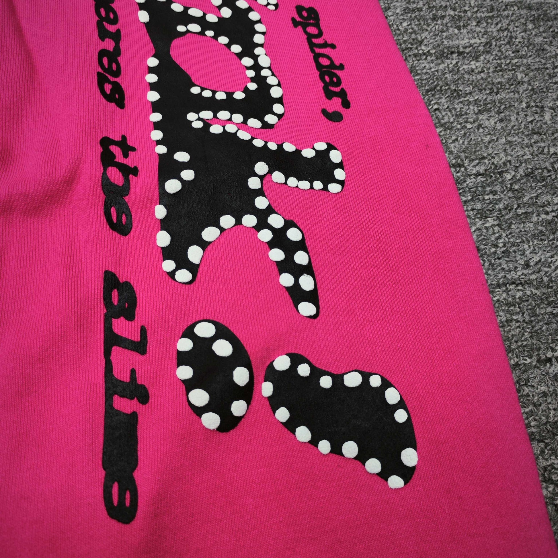 Close-up of black SP5DER puff-print graphic on pink P*NK V2 sweatpants