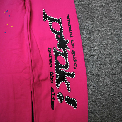Black SP5DER leg graphic and multicolor star prints on pink P*NK V2 sweatpants