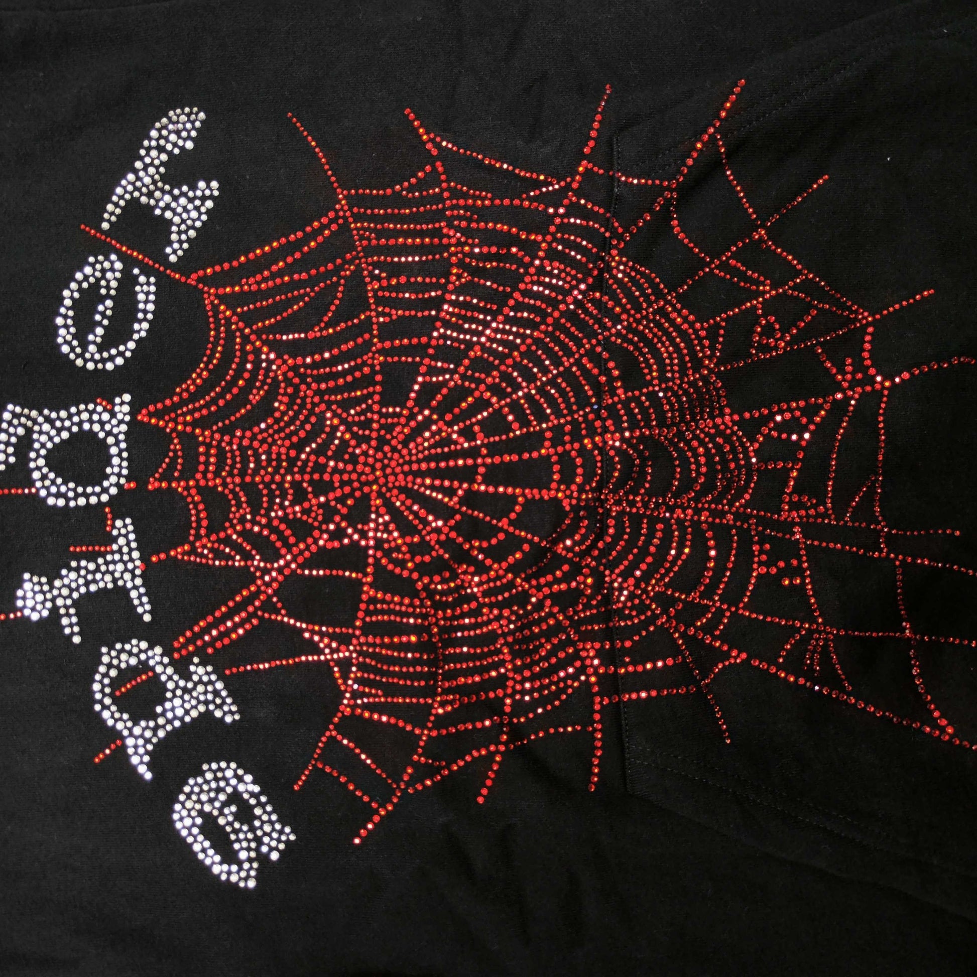 Full rhinestone artwork on Sp5der OG Web V2 Hoodie Black with silver logo and red spider web
Close-up of silver rhinestone SP5DER lettering on the black OG Web V2 Hoodie
Close-up of red rhinestone spider-web detailing on Sp5der OG Web V2 Hoodie Black
Side angle showing the raised three-dimensional rhinestone texture on Sp5der OG Web V2 Hoodie