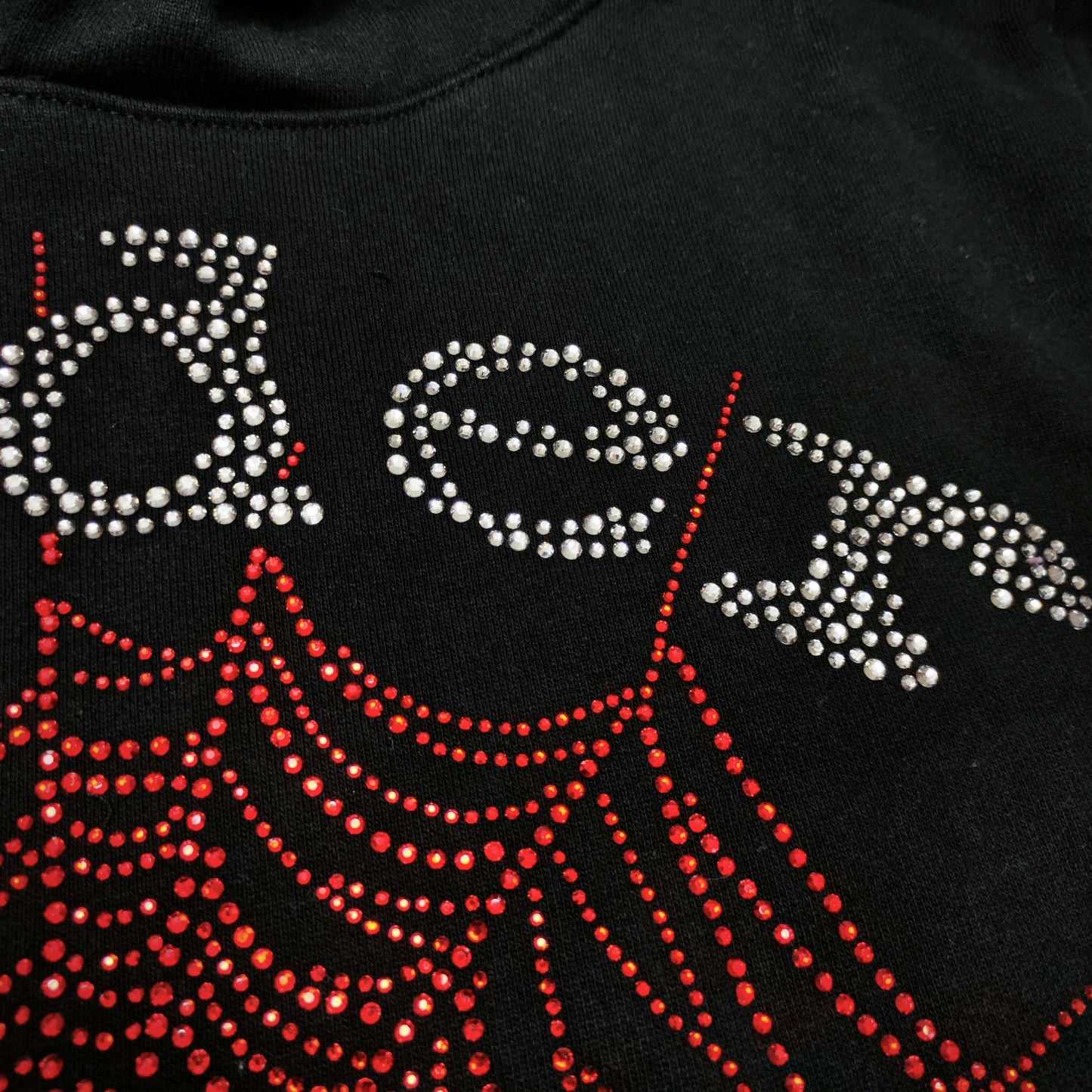 Full rhinestone artwork on Sp5der OG Web V2 Hoodie Black with silver logo and red spider web
Close-up of silver rhinestone SP5DER lettering on the black OG Web V2 Hoodie
Close-up of red rhinestone spider-web detailing on Sp5der OG Web V2 Hoodie Black
Side angle showing the raised three-dimensional rhinestone texture on Sp5der OG Web V2 Hoodie