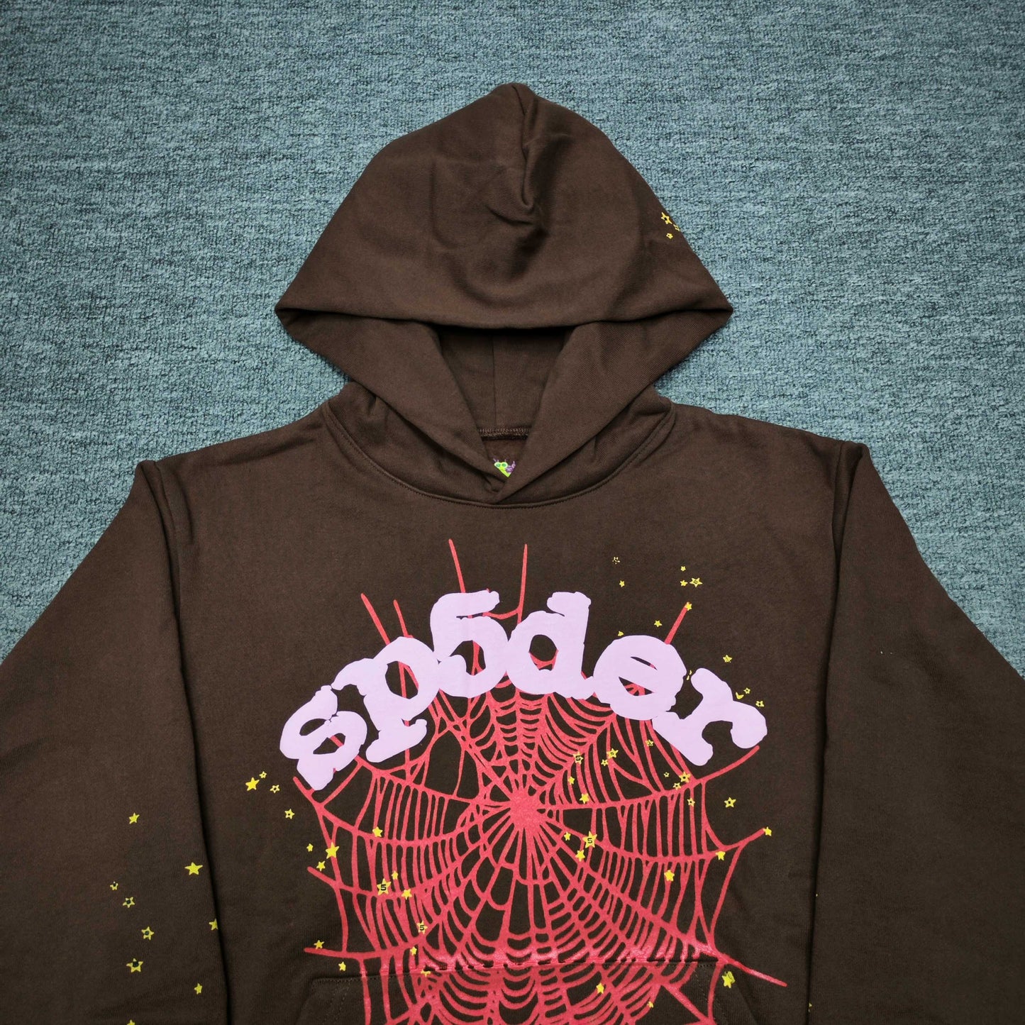 Full front artwork on Sp5der Web Hoodie Brown with pink puff logo, red web and yellow stars
Close-up of raised pink Sp5der puff-print lettering on the Brown Web Hoodie
Side angle showing the three-dimensional pink puff-print texture on Sp5der Web Hoodie Brown
Close-up of red spider-web artwork and yellow star details on Sp5der Web Hoodie Brown
