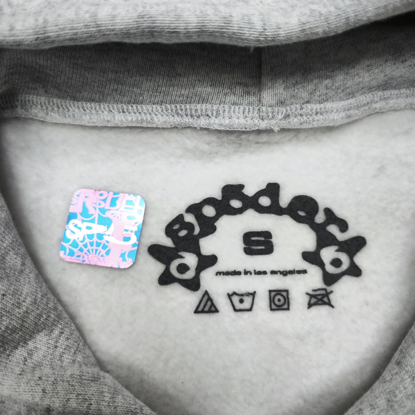 Sp5der OG Web Hoodie Heather Grey neck label and size tag detail
Sp5der OG Web Hoodie Heather Grey care label and washing instruction detail