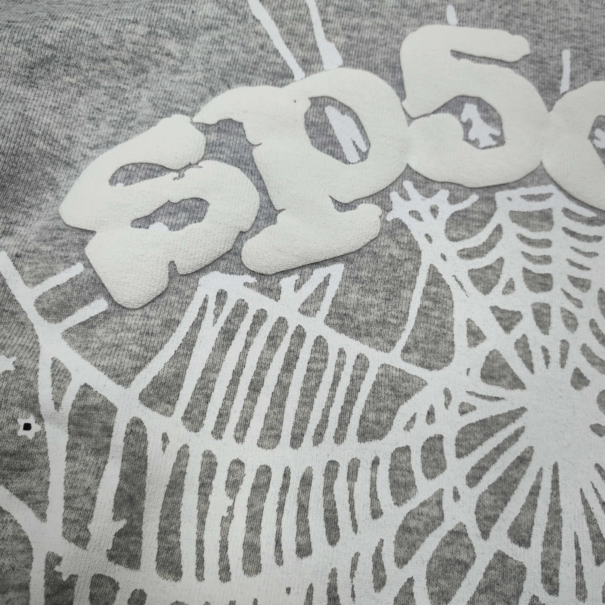 Full front artwork on Sp5der OG Web Hoodie Heather Grey with white puff logo and spider web
Full front artwork on Sp5der OG Web Hoodie Heather Grey with white puff logo and spider web
Side angle showing the three-dimensional white puff-print texture on Sp5der OG Web Hoodie
Close-up of white spider-web artwork on the front of Sp5der OG Web Hoodie Heather Grey