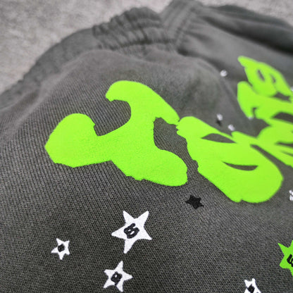 Neon green SP5DER logo and scattered star graphics on slate grey Wait Web sweatpants