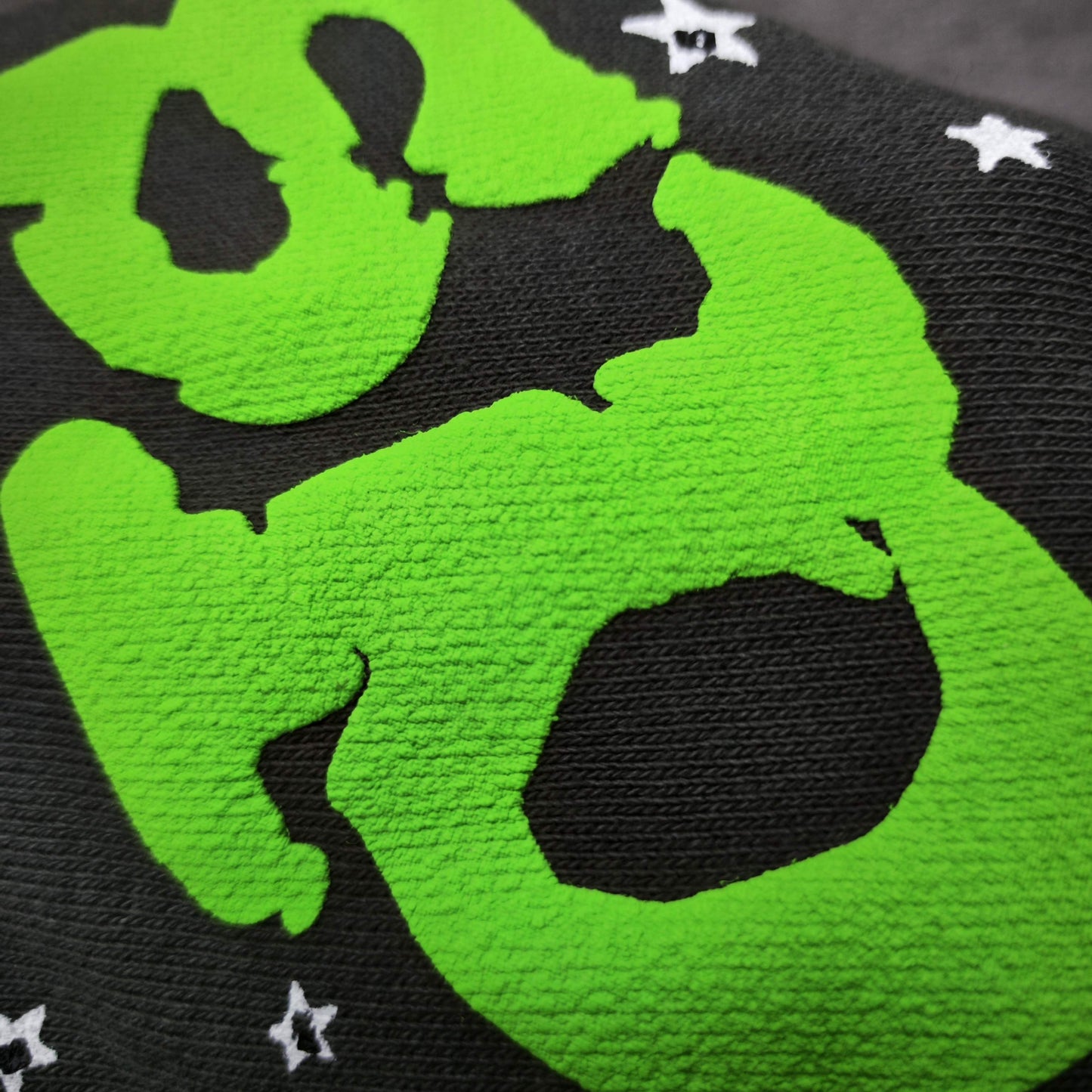 Close-up of neon green SP5DER puff-print logo on slate grey Wait Web sweatpants