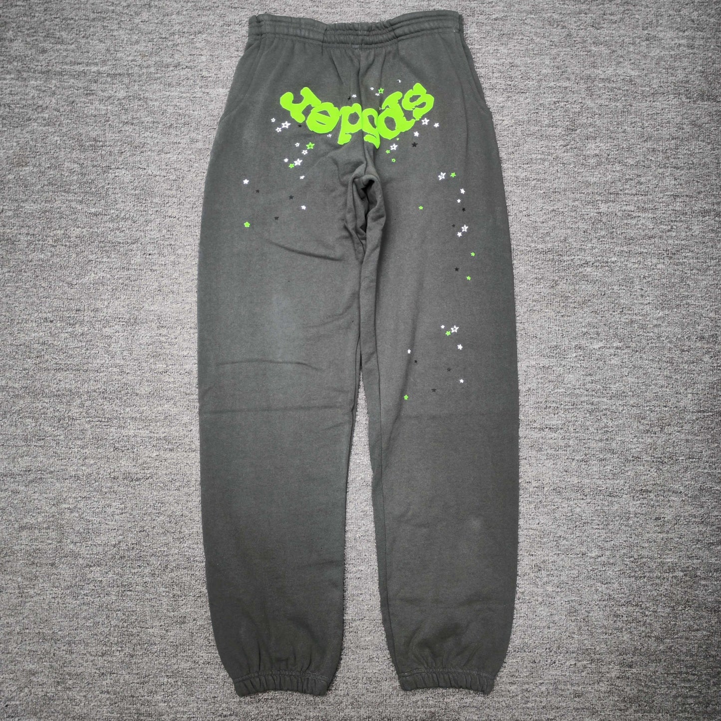 SP5DER Wait Web slate grey sweatpants front view with neon green logo and scattered stars