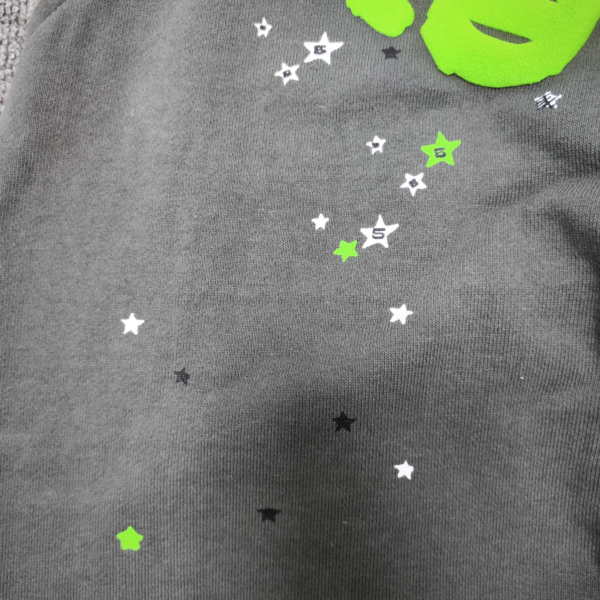 Scattered black white and green star graphics on SP5DER Wait Web sweatpants