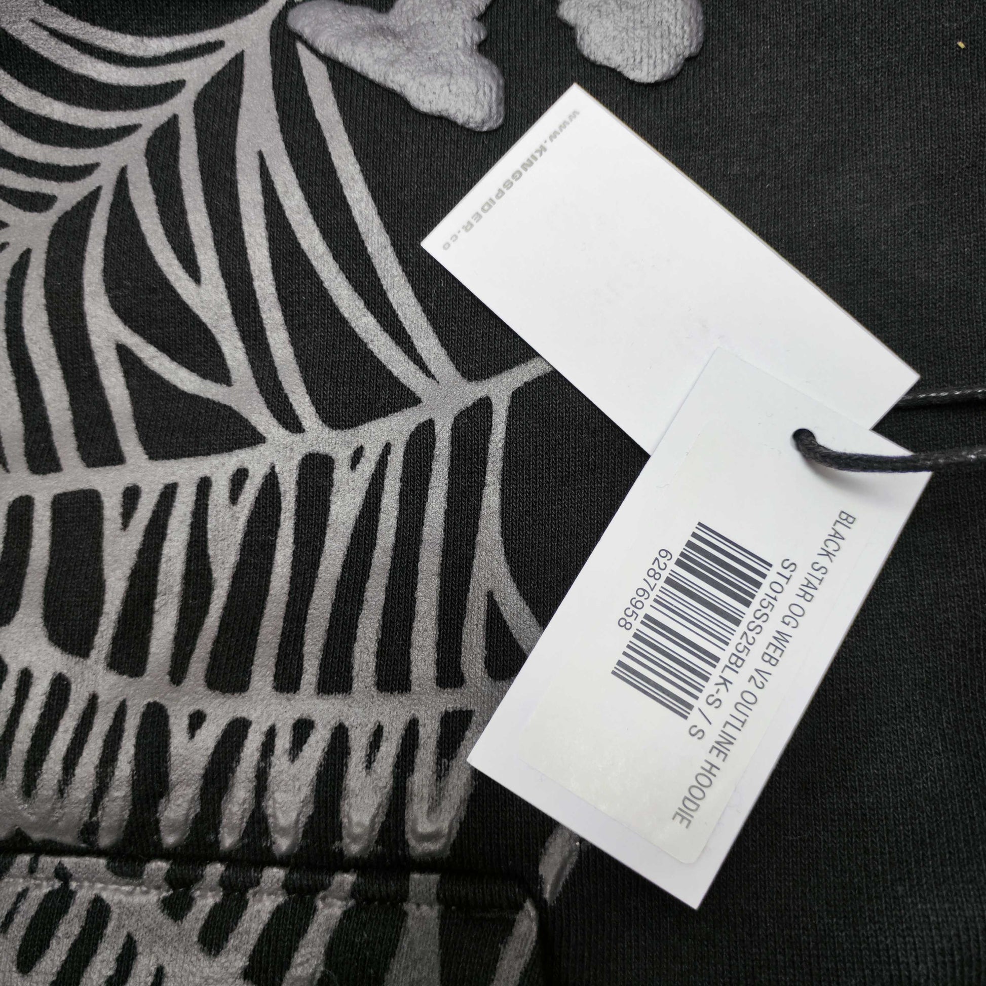 Full front artwork on Sp5der OG Web Hoodie Black with raised grey logo and tonal spider web
Close-up of raised dark-grey SP5DER lettering on the black OG Web Hoodie
Side angle showing the three-dimensional raised logo texture on Sp5der OG Web Hoodie Black
Close-up of tonal dark-grey spider-web artwork on Sp5der OG Web Hoodie Black
Close-up of tonal web graphic alignment around the kangaroo pocket on Sp5der black hoodie