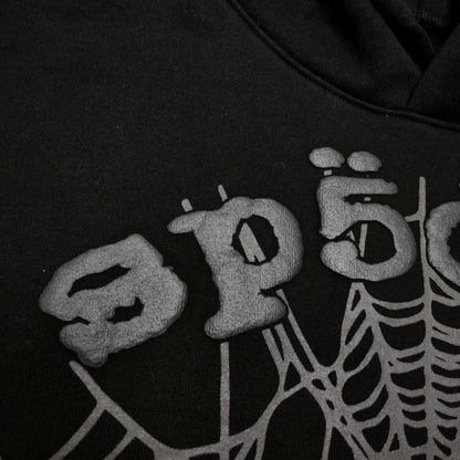 Full front artwork on Sp5der OG Web Hoodie Black with raised grey logo and tonal spider web
Close-up of raised dark-grey SP5DER lettering on the black OG Web Hoodie
Side angle showing the three-dimensional raised logo texture on Sp5der OG Web Hoodie Black
Close-up of tonal dark-grey spider-web artwork on Sp5der OG Web Hoodie Black
Close-up of tonal web graphic alignment around the kangaroo pocket on Sp5der black hoodie