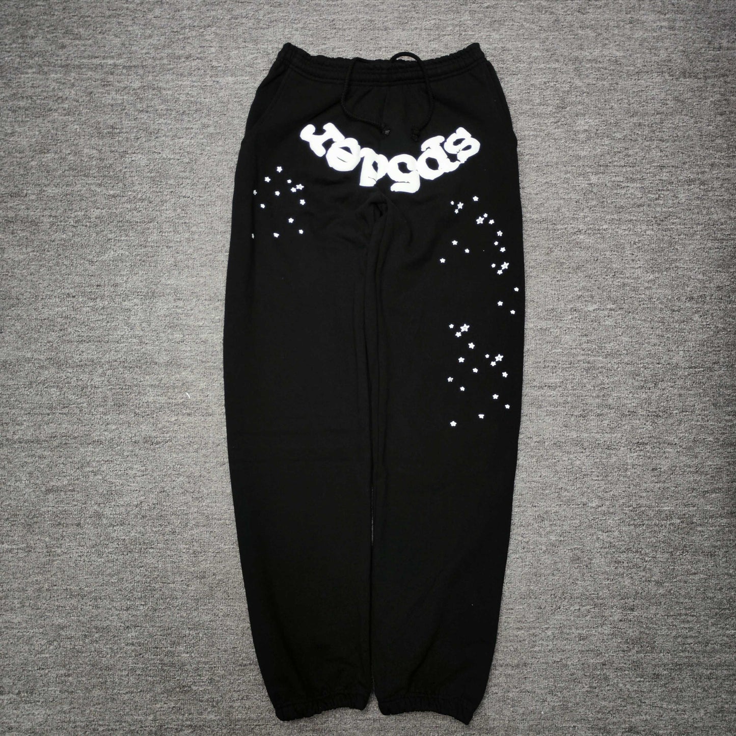 SP5DER OG Web black sweatpants front view with white logo and scattered star graphics