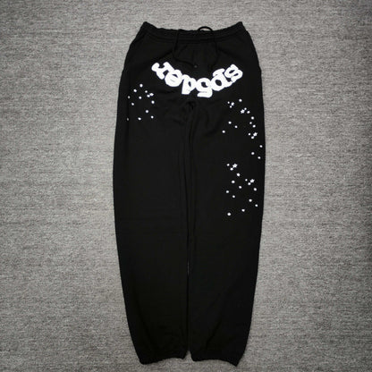 SP5DER OG Web black sweatpants front view with white logo and scattered star graphics