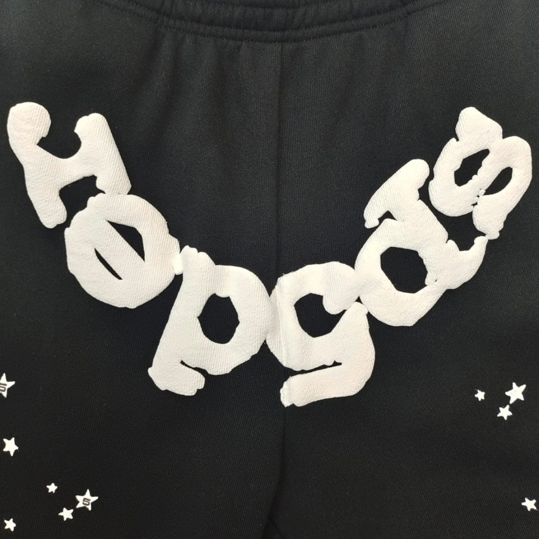 Close-up of white SP5DER puff-print logo on black OG Web sweatpants