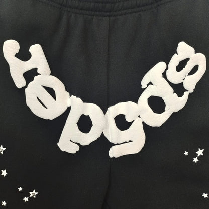Close-up of white SP5DER puff-print logo on black OG Web sweatpants